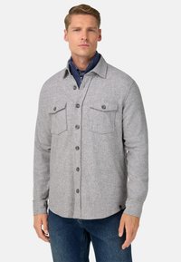 Grijs flanellen shirt met twee borstzakken en knoopsluiting. Heeft een kraag en een gestructureerde stof, gecombineerd met denim jeans.