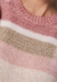 Pletený svetr s kulatým výstřihem, který má vodorovné pruhy v růžové, béžové a krémové barvě. Měkká textura a viditelné detaily šití.