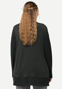 Mörkgrå långärmad tröja med lös passform. Har ribbtextur vid cuffarna och nederkanten. Slät tyg med en ren finish på baksidan.