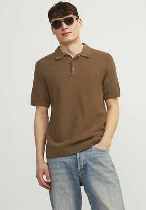 Polo din tricot maro, cu mâneci scurte, placket cu trei butoane, țesătură texturată. Purtați cu blugi albaștri deschiși și ochelari de soare negri.