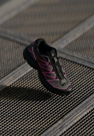 Black and pink running shoe with a textured upper, rounded toe, and integrated lacing system. Features logo and lightweight design.