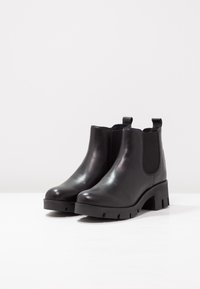 Botas Chelsea negras de cuero suave con suela gruesa, paneles laterales elásticos y lengüetas en la parte trasera para poner y quitar fácilmente.