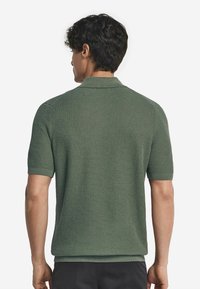 Grön texturerad pikétröja med korta ärmar, som har en ribbad krage och manschetter, samt en avslappnad passform.