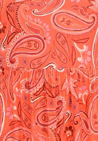 Czerwony materiał z wzorem paisley w odcieniach różu i fioletu, z kwiatowymi akcentami i detalem w postaci marszczenia w pasie. Gładka faktura.