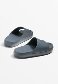 Grijze rubberen sandalen met een gestructureerde bovenkant, open design en platte zolen. Opvallende groeven aan de onderkant voor grip. Lichtgewicht constructie.