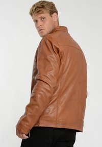 Brun læderjakke med en glat tekstur, klassisk krave og lynlåslommer, vist fra en let vinklet vinkel.