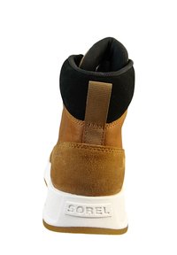 Brązowe zamszowe i czarne materiałowe sneakersy typu high-top z białą gumową podeszwą, posiadające tylne uchwyt do zakładania oraz wytłoczone logo na pięcie.