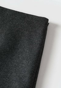 Donkergrijze viltstof met een zachte textuur, in een hoek gevouwen, toont fijne vezels en een gladde oppervlakte zonder zichtbare patronen of accenten.