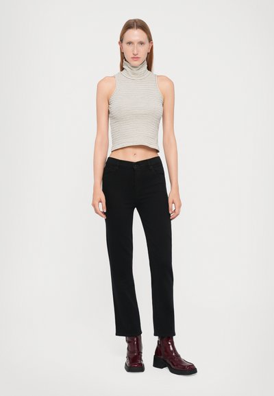 Top corto senza maniche a righe in beige e grigio scuro, abbinato a pantaloni neri a gamba dritta. La modella indossa stivali alla caviglia bordeaux lucidi.