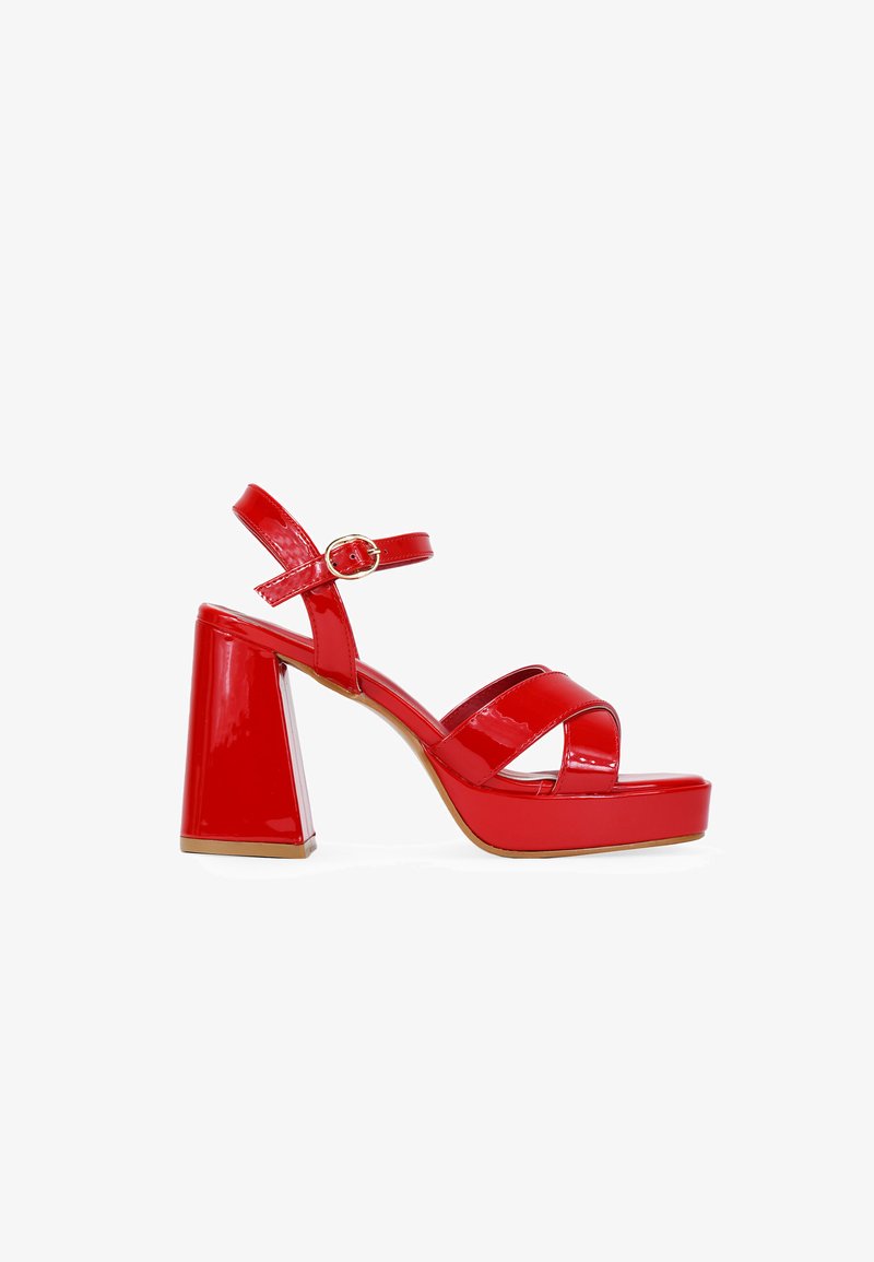 Sandalias de plataforma de charol rojo con un chunky heel, tiras en el tobillo con un cierre dorado y múltiples tiras cruzadas en la puntera.