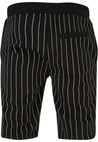 Pantaloni scurți negri cu dungi albe, fabricați dintr-un material moale. Au un talie elastică și un singur buzunar în spate.