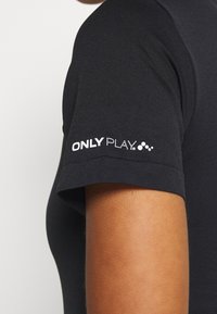 Camisa atlética negra con un diseño ajustado, que presenta mangas cortas y el logo "ONLY PLAY" en blanco en la manga. Textura suave.