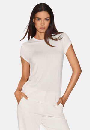 Witte t-shirt met korte mouwen en ronde hals, gemaakt van zachte stof, met een relaxte fit en een lichte stretch, gedragen met de handen in de broekzakken.