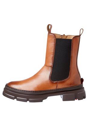 Tan leren Chelsea-boot met een zwart elastische zijpaneel en een dikke donkerbruine zool, met trekflappen aan de voorkant en achterkant.