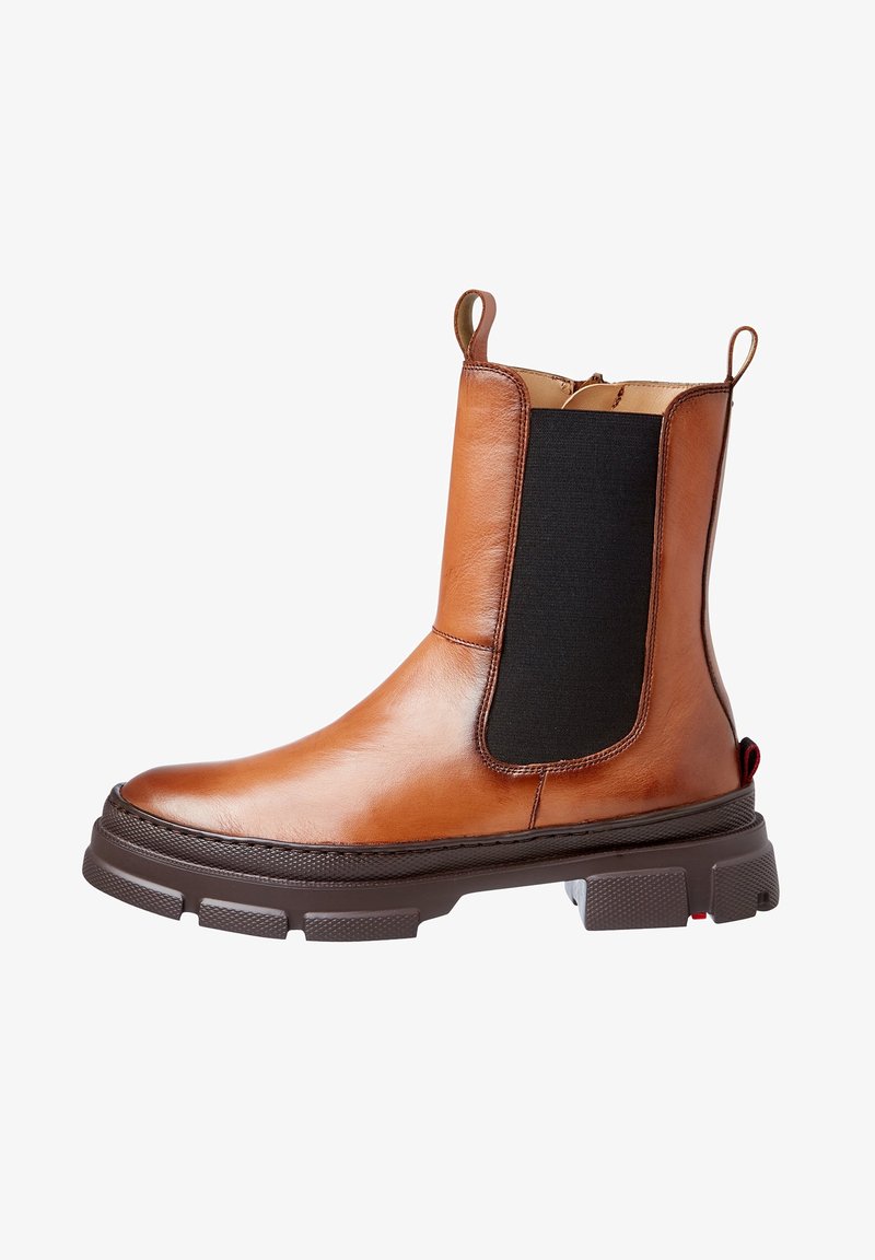 Botte Chelsea en cuir tan avec panneau élastique noir sur les côtés et semelle épaisse marron foncé, languettes à l'avant et à l'arrière.