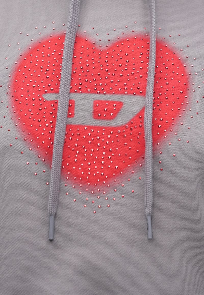 Gray sweatshirt featuring a large red heart design adorned with small rhinestones. Hood with drawstrings in matching gray.