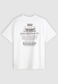 Valkoinen puuvillapaita, jossa on käytetty Levi Strauss & Co. -grafiikka tummanharmaana, lyhythihaisena ja pyöreällä pääntiellä.