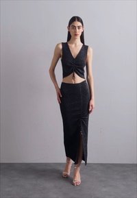 Musta, kimaltava kahden osan setti, jossa on istuva crop top V-kaula-aukon ja rypytettyjen yksityiskohtien kanssa, yhdistettynä kynähameeseen, jossa on sivureikä.