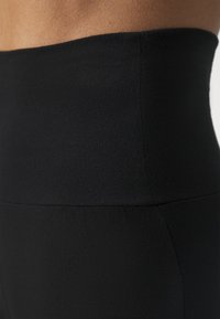 High-waisted black leggings made from stretchy fabric, featuring a smooth texture and seamless design for comfort and flexibility.