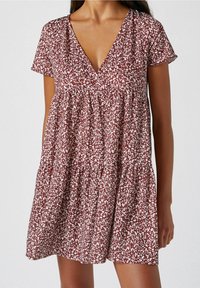 Vestido de estampado floral en rojo y blanco con escote en V y mangas cortas. Presenta un diseño en capas y un ajuste suelto y fluido.