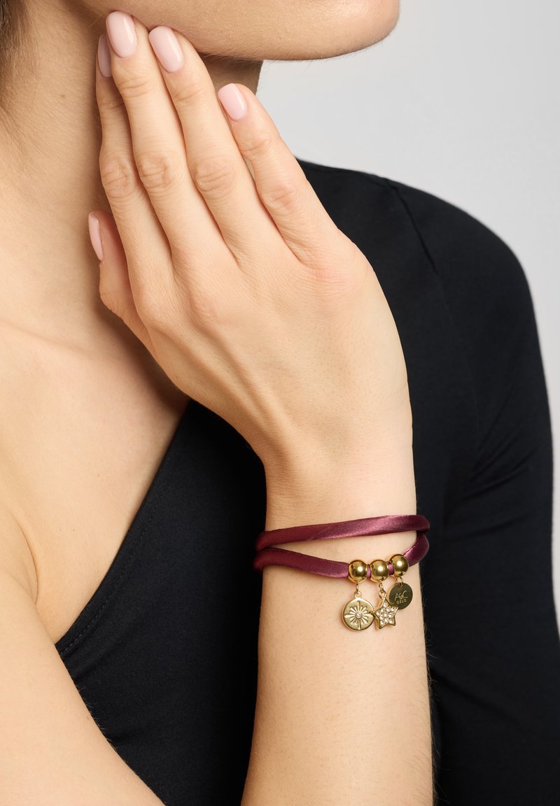Burgundy satin bracelet with gold-tone accents. Features decorative charms: a flower and star, and smooth spherical beads.