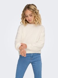 Weißer, flauschiger Pullover mit langen Ärmeln, rundem Ausschnitt und geripptem Saum, kombiniert mit hellblauen Jeans. Weiche Textur, entspannte Passform.