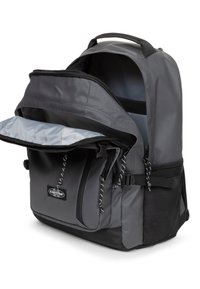 Zaino grigio con un ampio scomparto principale e tasca anteriore con zip. Presenta accenti neri e tessuto testurizzato, con spallacci regolabili.
