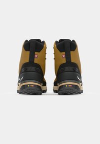 Rudi ir juodi žygio batai su tekstūruota gumine padu, paminkštintu apykakle ir spalvingu akcentu kulne. Šoninė raištelių sistema.