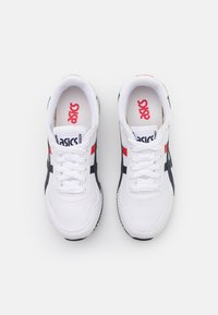 Valkoiset verkkokangas urheilukengät, joissa on tummansinisiä ja punaisia yksityiskohtia. Kenkien suunnittelussa on nyöritys ja pehmustettu kaulus mukavuutta varten. Logo näkyy kengän kielessä.