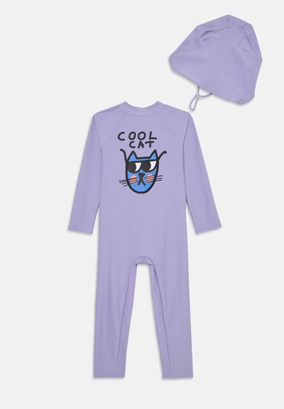 Μωβ φόρμα με μακριά μανίκια και γραφικό "Cool Cat" με ροζ λεπτομέρειες; περιλαμβάνει αντίστοιχη μωβ περούκα. Μαλακό, ελαστικό ύφασμα για άνεση.