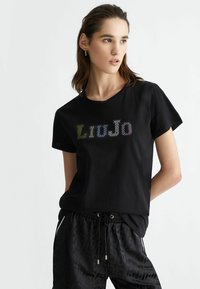 T-shirt in cotone nero con maniche corte, caratterizzato da un logo in strass multicolore "Liu Jo" sul petto. Texture liscia.