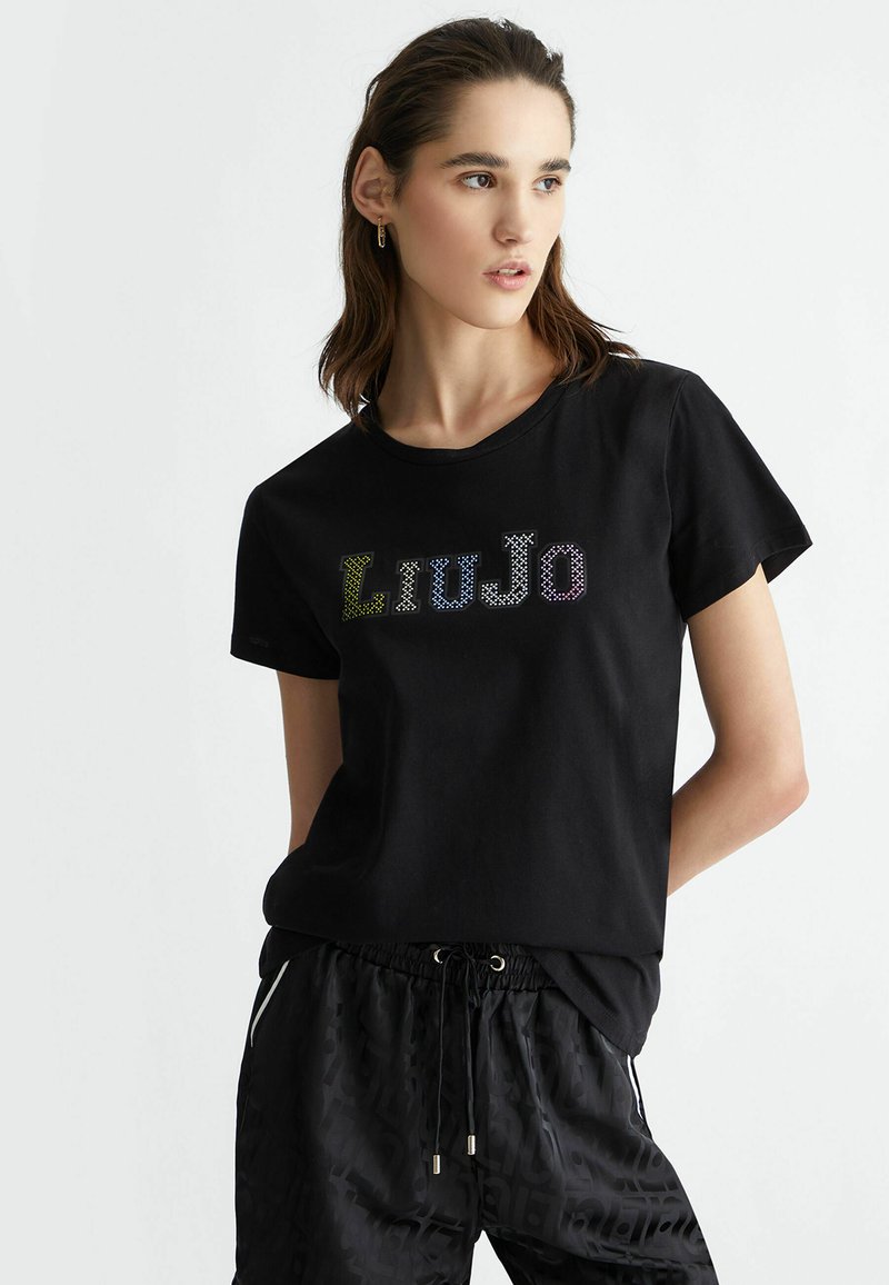T-shirt in cotone nero con maniche corte, caratterizzato da un logo in strass multicolore "Liu Jo" sul petto. Texture liscia.