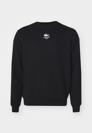 Sweatshirt negru cu guler rotund, mâneci lungi și text alb cu logo-ul Lacoste pe piept. Fabricat din material moale de bumbac.