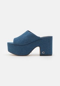 Muli in denim con piattaforma e tacco spesso e arrotondato. Parte superiore in tessuto blu, design a punta aperta e sottile logo accentuato sul tacco. Texture liscia.