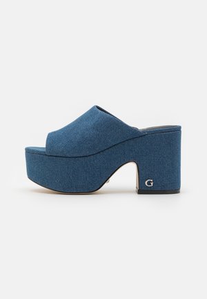 Muli in denim con piattaforma e tacco spesso e arrotondato. Parte superiore in tessuto blu, design a punta aperta e sottile logo accentuato sul tacco. Texture liscia.