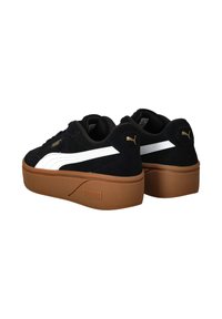 Sneakers platform in suede nero con una striscia bianca, suola in gomma marrone e logo dorato sul tacco e sul lato. Forma della punta arrotondata.