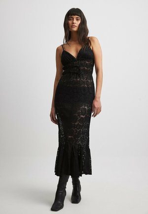 Black lace midi dress with a fitted bodice, ruffled detailing, thin straps, and a flared hemline. Textured lace pattern with sheer sections.