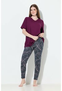 Camiseta de cuello en V púrpura combinada con leggins azul marino que presentan un patrón abstracto en blanco y rosa, textura suave y diseño ajustado.