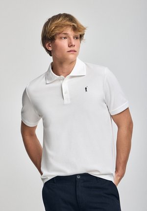 T-shirt polo blanc en coton, avec un col classique, une patte à trois boutons et un petit logo noir sur la poitrine.