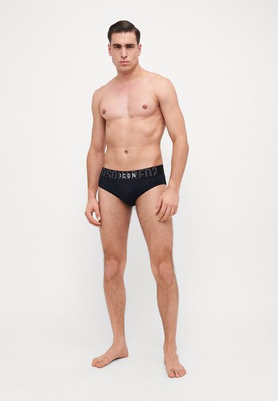 Schwarze Baumwollslips mit einem breiten elastischen Bund, der die "ICON"-Markierung trägt. Der Stoff wirkt glatt und hat eine enge Passform, ohne sichtbare Muster.