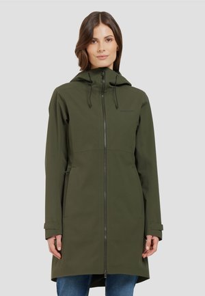 Frau trägt eine lange, olivgrüne wasserdichte Jacke mit Kapuze, Frontreißverschluss und Seitentaschen, steht vor einem schlichten hellen Hintergrund.