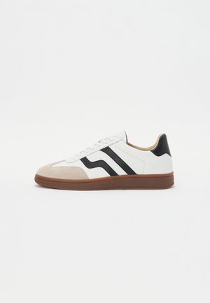 Weißer Sneaker mit schwarzen Streifenakzenten, Wildleder-Zehenkappe und brauner Gummisohle. Glattes Lederoberteil mit rundem Design.