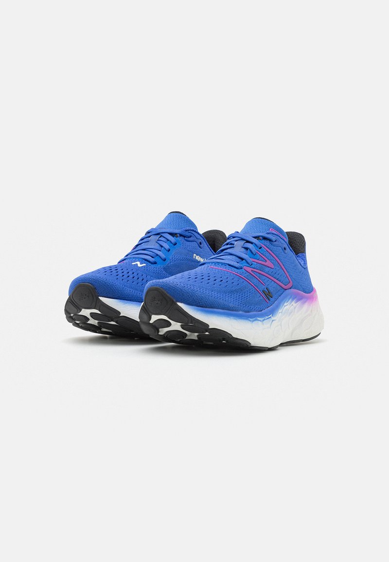 Zapatillas de correr azules con parte superior de malla, acentos en rosa contrastantes y una entresuela blanca texturizada. Cuenta con una suela exterior de goma negra.