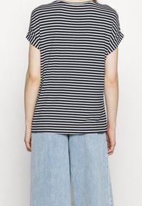 Striped t-shirt with short rolled sleeves, featuring dark navy and white stripes. Fabric appears soft. Paired with light blue wide-leg jeans.