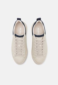 Beige leather sneakers with navy accents, round toe, textured laces, and pull tabs on the heel; flat rubber soles.
