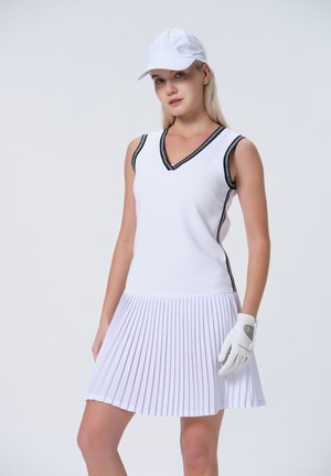White golf dress with pleated skirt, black accent on neckline, made from stretchy fabric. Worn with a white cap and glove.
