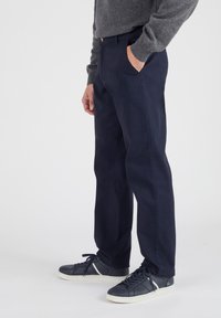Navy chinos van katoen, met een rechte pasvorm, zijzakken en een klassieke knoopsluiting. Gecombineerd met navy sneakers.