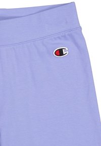 Shorts de sport lilas avec une taille élastique et un petit logo brodé en noir et rouge sur le côté gauche. Tissu doux et lisse.