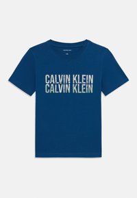 Mėlynas medvilnės marškinėliai su tekstu "CALVIN KLEIN", atspausdintu šviesesne spalva per krūtinę. Klasikinis apvalus kaklas ir trumpomis rankovėmis.