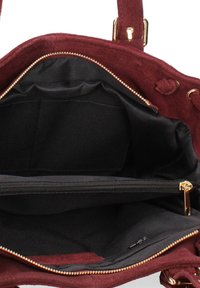 Sac à main en suède bordeaux avec un compartiment principal zippé, doublure en tissu noir, poches intérieures et accents en métal doré.